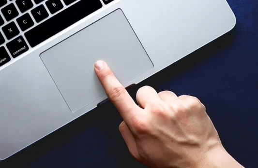 Hand using laptop touchpad indoors, highlighting user interaction and focus on touchpad repair service.